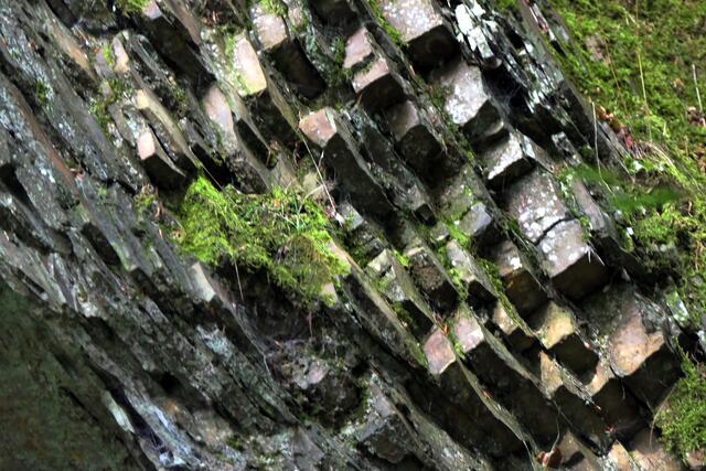 Schieferformationen an der Basis eines bewaldeten Hügels