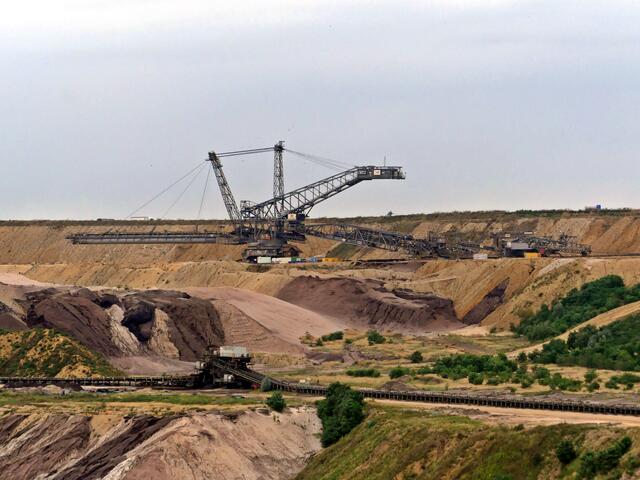 Weit entfernt am östlichen Rand der Grube, ein Absetzer beim Verfüllen der Grube.