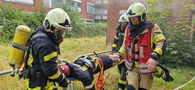 Eine 80 Kilo schwere Puppe symbolisiert eine der hilflosen Personen. Sie wird von mehreren Einsatzkräften aus dem "brennenden" Haus geborgen.
