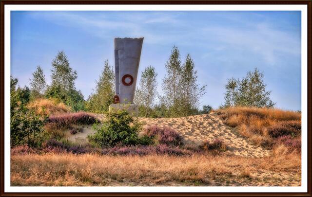Das Denkmal hat die Form einer Tragfläche des britischen Bombers vom Typ „Lancaster", der durch einen deutschen Nachtjäger am 12. März 1943 abgeschossen worden ist. Eine der Tragflächen blieb in dem Sand der Maasdünen am Absturzort in dieser Lage stecken. Alle Besatzungsmitglieder kamen bei dem Absturz ums Leben.