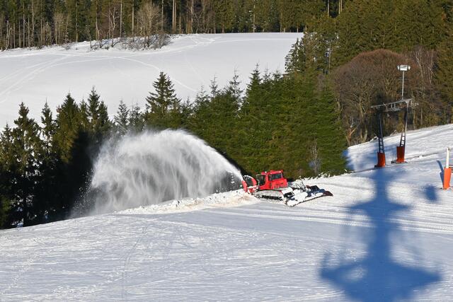 Neben dem Schatten des Fernmeldeturms wird mit der Pistenraupe der Skihang für den Betrieb am Wochenende vorbereitet.