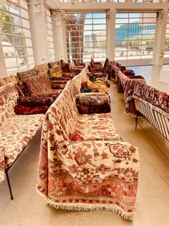 Blick in die aktuelle Ausstellung im Centre Pompidou, die der Mülheimer Kunstverein KKRR erst kürzlich besuchte - hier wurden die Teppiche zu Sofas umgestaltet.

Die Reaktionen auf „Unendlicher Sonntag“ im Centre Pompidou-Metz sind bisher überwiegend positiv – und oft auch ein bisschen verblüfft.

Besucherinnen auf Social Media  beschreiben die Ausstellung als „traumartig“, „entschleunigend“ und „radikal offen“. Besonders die Teppichlandschaft im Foyer wird häufig fotografiert und kommentiert – viele nennen sie „le salon du musée“ oder „un espace de respiration“. Der Hashtag #dimanchesansfin ist voll von Eindrücken, Selfies auf Teppichen und Momentaufnahmen der Ruhe.

In einem kurzen Beitrag des Saarländischen Rundfunks wird die Schau als „ungewöhnlich“ und „mutig“ beschrieben – mit über 400 Werken, darunter viele von Maurizio Cattelan, die sich über mehrere Etagen erstrecken. Die Reporter*innen betonen, dass die Ausstellung nicht nur Kunst zeigt, sondern das Museum selbst in eine Art begehbare Installation verwandelt.

Auch Kunstblogs und kleinere französische Medien loben die Idee, das Museum als sozialen Raum zu denken – ein Ort, an dem man nicht nur schaut, sondern auch verweilt, sich begegnet und vielleicht sogar ein bisschen träumt.

Kurz gesagt: Die Schau polarisiert nicht, sie entschleunigt. Und sie scheint genau das zu tun, was ihr Titel verspricht – einen Sonntag zu schaffen, der nicht endet.   
So motiviert entstand der "Mülheimer Kunstsonntag" - ein Format des Mülheimer Kunstvereins KKRR - demnächst mehr! | Foto: Mülheimer Kunstverein und Kunstförderverein KKRR