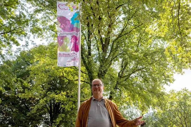 Das Foto zeigt Pfarrer Winterberg an der Salvatorkirche vor der Fahne, die fürs Mitmachen bei "Das Ruhrgebiet spricht" wirbt.
Foto: Rolf Schotsch
