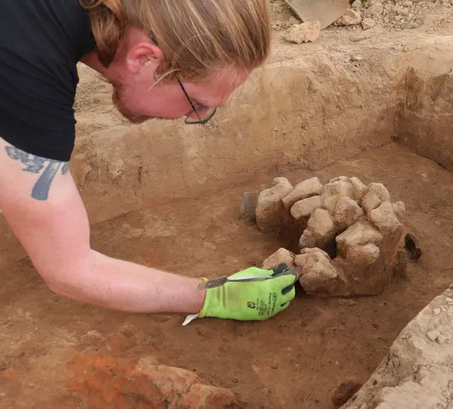 In einer der eisenzeitlichen Gruben fand sich eine ungewöhnliche Ansammlung von Steinen, die hier vorsichtig freipräpariert werden.
Foto: LQ Archäologie/C. Bariszlovich