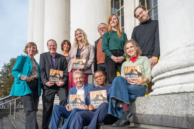 Das Foto wurde bei der Vorstellung der Dokumentation „20 Jahre Jugendclub Spieltrieb im Theater Duisburg“ aufgenommen. Stehend von links: Katharina BöhrkeSpieltrieb Theaterpädagogin, Intendant Michael Steindl, Britta Fehlberg, Theater Duisburg, Kulturdezernentin Linda Wagner, Wolf-D. Lipka, stellvertr. Vorsitzender des Vereins Förderer der Duisburger Theater-Kultur, Damira Schumacher, Regieseurin, Lukas Giese, Spieltrieb. Sitzend von links: Heinz Pudell, Schatzmeister des Vereins Förderer der Duisburger Theater-Kultur, Amanda Kirchner und Lulu Feuser, beide Spieltrieb.
Foto: Tanja Pickartz / Stadt Duisburg
