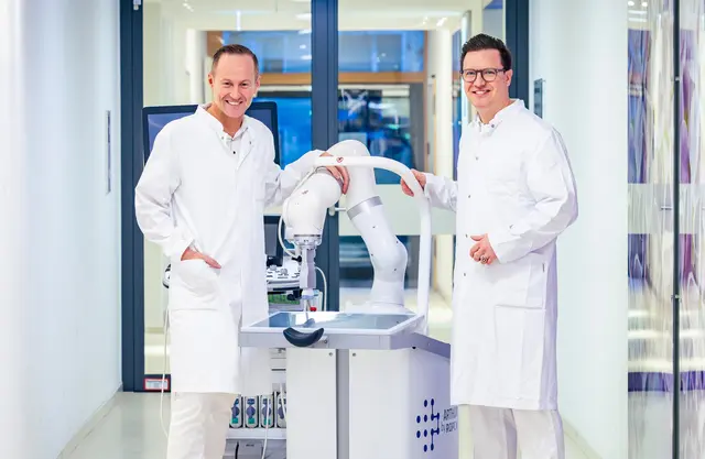 Prof. Dr. Xenofon Baraliakos (l.), Ärztlicher Direktor des Rheumazentrum Ruhrgebiet, und Oberarzt Prof. Dr. Philipp Sewerin (r.) mit dem Ultraschallroboter, der die Ärzte mit KI bei einer schnelleren und genaueren Diagnose unterstützt. | Foto: St. Elisabeth Gruppe