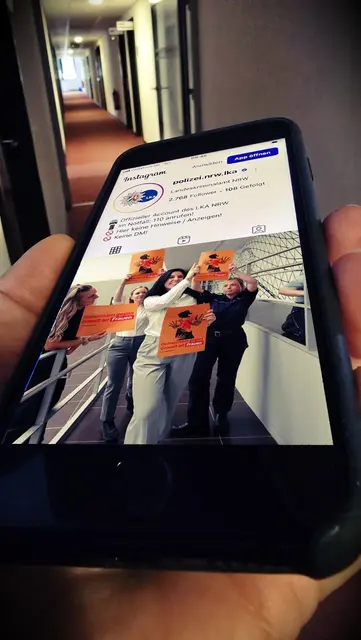 Bild LKA NRW: In Hand gehaltenes Smartphone auf dessen Screen der Instagram Kanal des LKA NRW und eine Tanzszene aus dem Video zum Tag gegen Gewalt gegen Frauen zu sehen ist. | Foto: Landeskriminalamt Nordrhein-Westfalen
