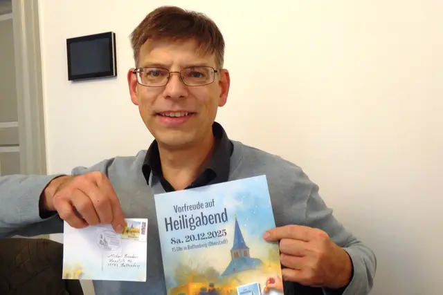Michael Bienhaus präsentiert die Sonderpostkarte mit dem Entwurf der Sonderbriefmarke und dem Sonderstempel für den 20.12.2025.