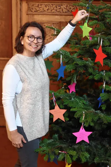 Kerstin Wositsch, Leiterin der Kinder- und Jugendhilfe bei der Caritas Ruhr-Mitte in Hattingen, hängt einen Wunschstern an den Baum. Foto: Caritas Ruhr-Mitte