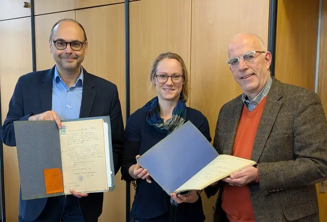 Foto (v. l. n. r.): Schulleiter Sascha Busse mit der ältesten Einheit des Schularchivs – der Lehrerpersonalakte des Biologen Johannes Tholen (ab 1904) –, daneben Archivarin Lisa Hampel und Geschichtslehrer Dr. Klaus-Peter Kirstein mit Abschlussarbeiten im Fach Deutsch vom Ostertermin 1922 (Best. 473 Nr. 1, 56).  | Foto: Oxana Riesner