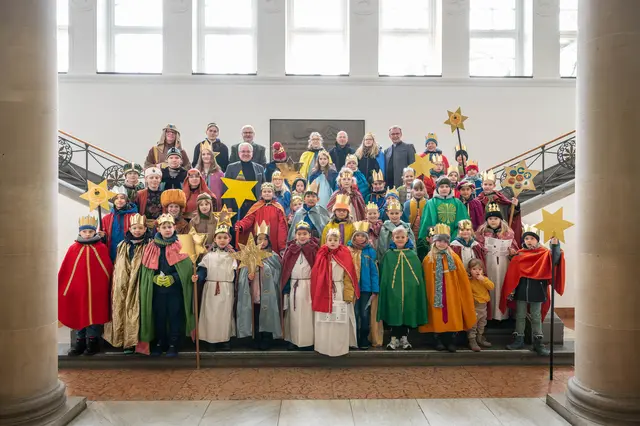 Die Sternsinger zusammen mit Oberbürgermeister Marc Buchholz (2. Reihe von hinten, 3. von links), Pfarrer Christian Böckmann (St. Mariä Himmelfahrt und St. Barbara – hinterste Reihe, 2. von rechts), Bürgermeister Markus Püll (hinterste Reihe, 3. von links) und Beigeordneter Felix Blasch (hinterste Reihe, 4. von rechts) auf der Treppe des Standesamtfoyers.
Foto: Helena Grebe

