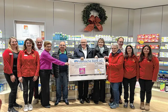 Familie Köster mit Team bei der Scheckübergabe am 19.12.2025 an Mendener in Not e.V. vertreten durch Klaus Ullrich (Mitte), Rainer Zentgraf (5.v.l.), Veronika Czerwinski (4.v.r.) und Cristina Gummert (5.v.r.). Foto: Apotheke Köster
