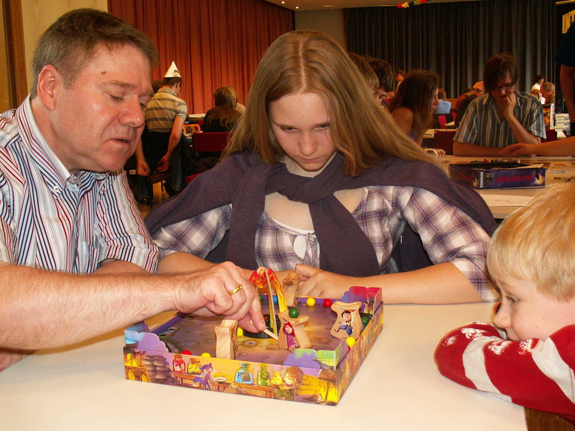 Vater bewegt den Zauberlehrlinge und die Kinder schauen gespannt zu. "Die kleinen Zauberlehrlinge" (Drei Magier Spiele)