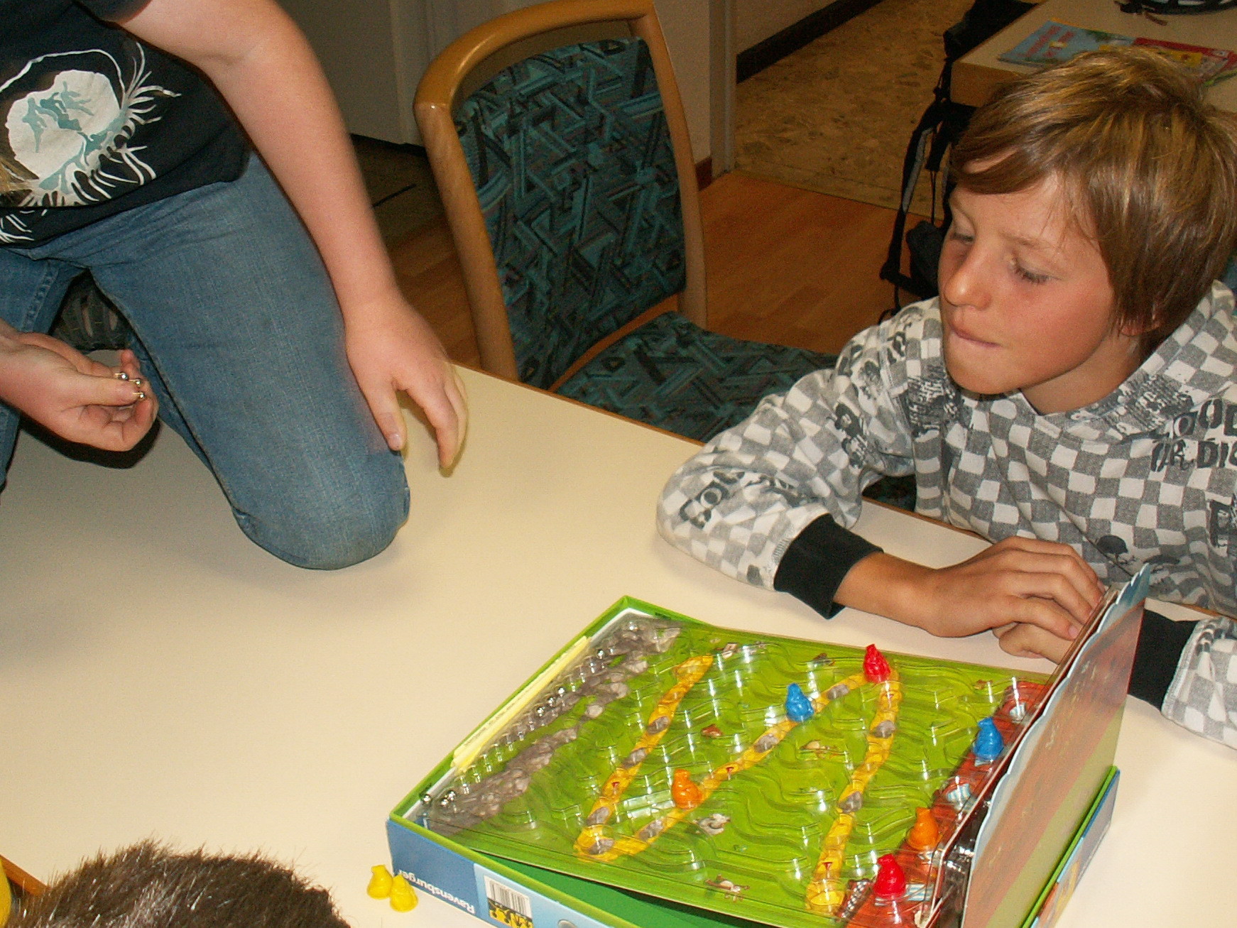 Knieend auf dem Tisch werden die Kugeln gestartet bei "Das große Kullern" von Ravensburger.