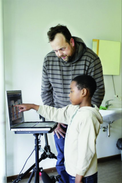 Fotograf Andreas Teichmann und ein Schüler beim Auswahlverfahren nach dem Fotoshooting. Das Kind entscheidet, welches seiner Selbstportraits in die Ausstellung kommt. Foto: Taube