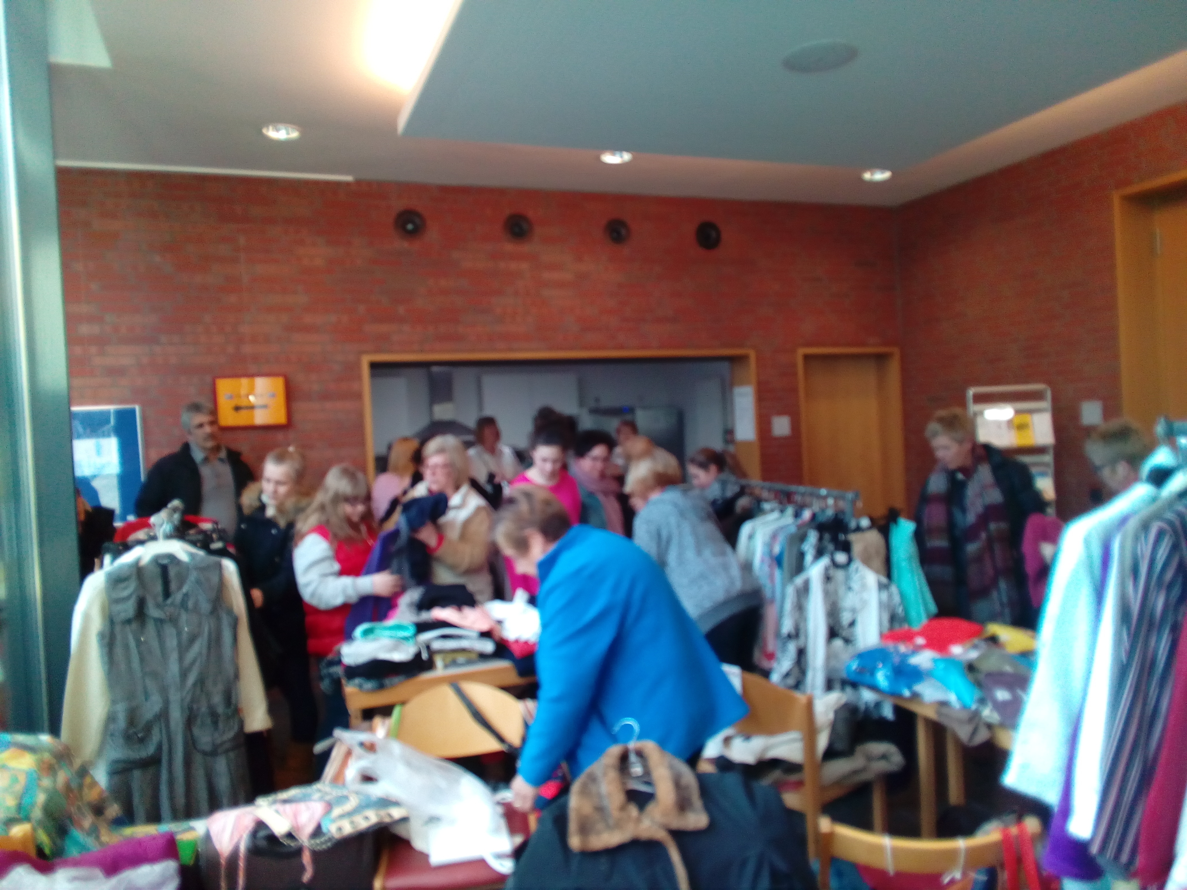 Im Saal und im Foyer des Martinszentrums freuen sich Frauen über schöne Kleidungsstücke und gute Verkäufe und an Kaffee und Kuchen