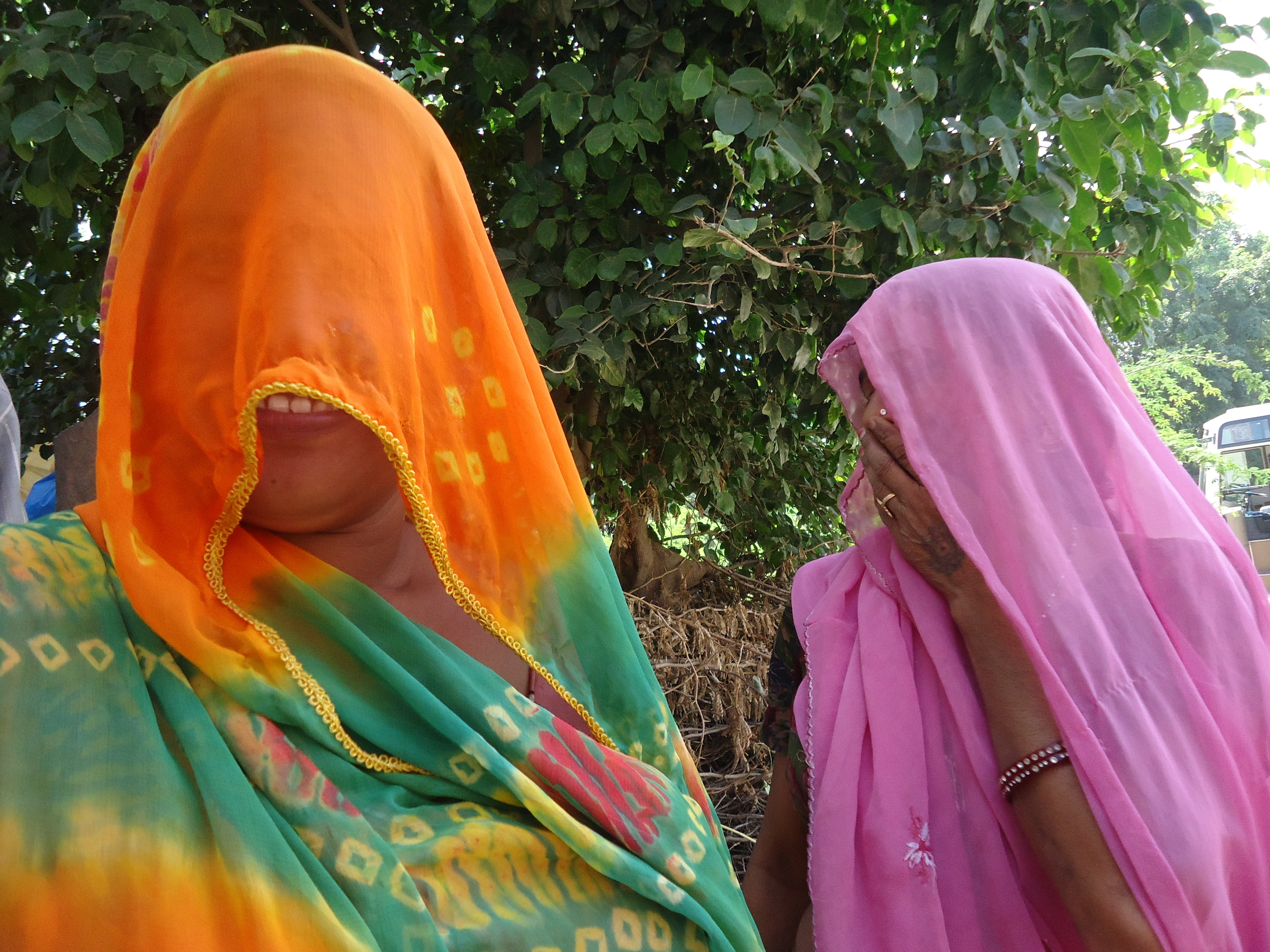 in Indien. die Frauen verschleiern ihre gesichter vor blicken. eine hält noch die Hand vors gesicht.