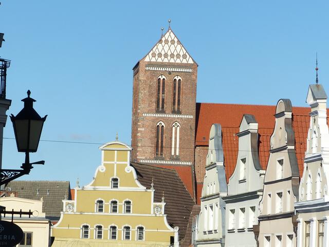 Wismar. Das Gebäude betont dominant das Ende der Krämerstr. Es steht unter Denkmalschutz und früher befand sich dort die "Alte Löwenapotheke". Heute ist hier ein Café. Im Hintergrund ist die St. Nikolaikirche zu sehen.